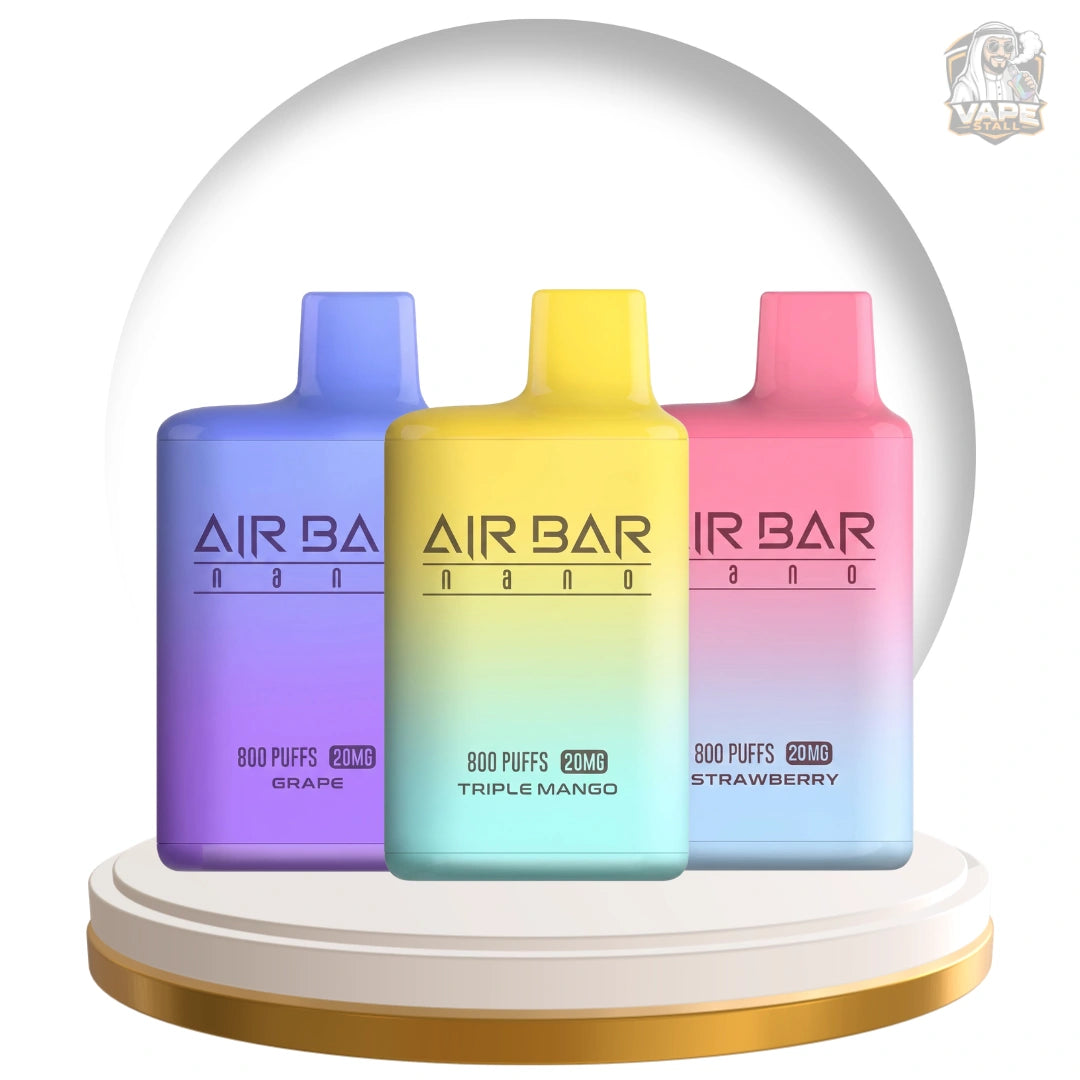 Three AIR BAR vape devices in a snow globe display: Grape purple, Triple Mango yellow-green, and Strawberry pink, on a white and gold base.