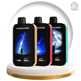 Three MASKING Boost disposable vape devices in black, gold, red, and teal, displayed side-by-side on a white and gold circular pedestal. The vapes feature landscape-themed screens showing a starry night, shooting stars, and an icy mountain scene.