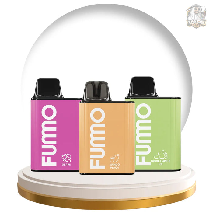 Three FUMO disposable vape devices in Grape, Mango Peach, and Double Apple Ice flavors, displayed side-by-side on a white and gold circular pedestal with a large white dome backdrop.