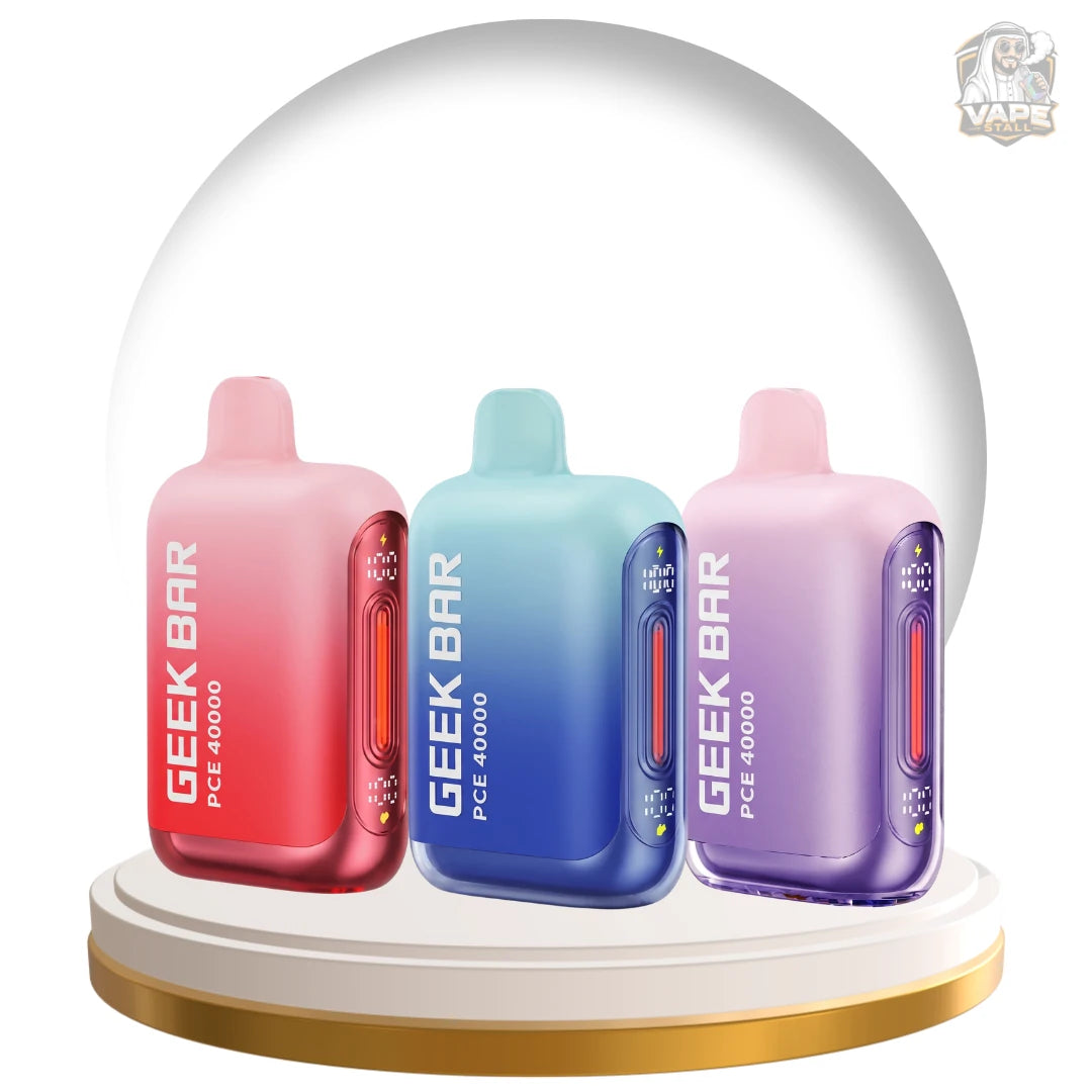 Three Geek Bar PCE 4000 disposable vape devices in pink-red, blue, and purple gradient colors, displayed under a clear glass dome on a white and gold circular base.