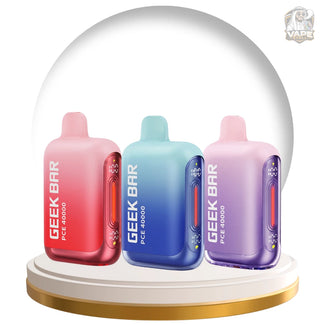 Three Geek Bar PCE 4000 disposable vape devices in pink-red, blue, and purple gradient colors, displayed under a clear glass dome on a white and gold circular base.