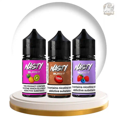Three NASTY BURST e-liquid bottles displayed side by side on a white pedestal inside a clear dome-shaped display. The bottles are shown in three flavors: Pineapple and Kiwi (pink label), Cola (brown label), and Raspberry and Blueberry (purple label).
