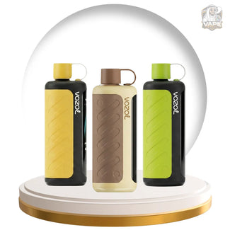 Three Voozol vape devices displayed on a white and gold rotating platform, set against a large white circular backdrop. The devices come in three colorways: yellow, beige/brown, and green, all with black side panels and white Voozol branding.