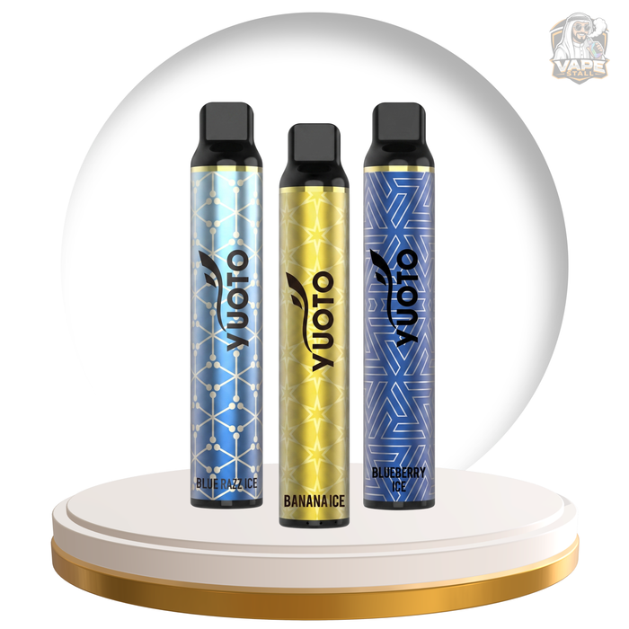 Three Yuoto disposable vape devices standing upright on a white and gold circular pedestal. The left device is light blue with a geometric pattern and labeled 'Blueberry Ice'; the center device is metallic gold with a geometric pattern and labeled 'Bananaice'; the right device is dark blue with a geometric pattern and labeled 'Blueberry Ice'.